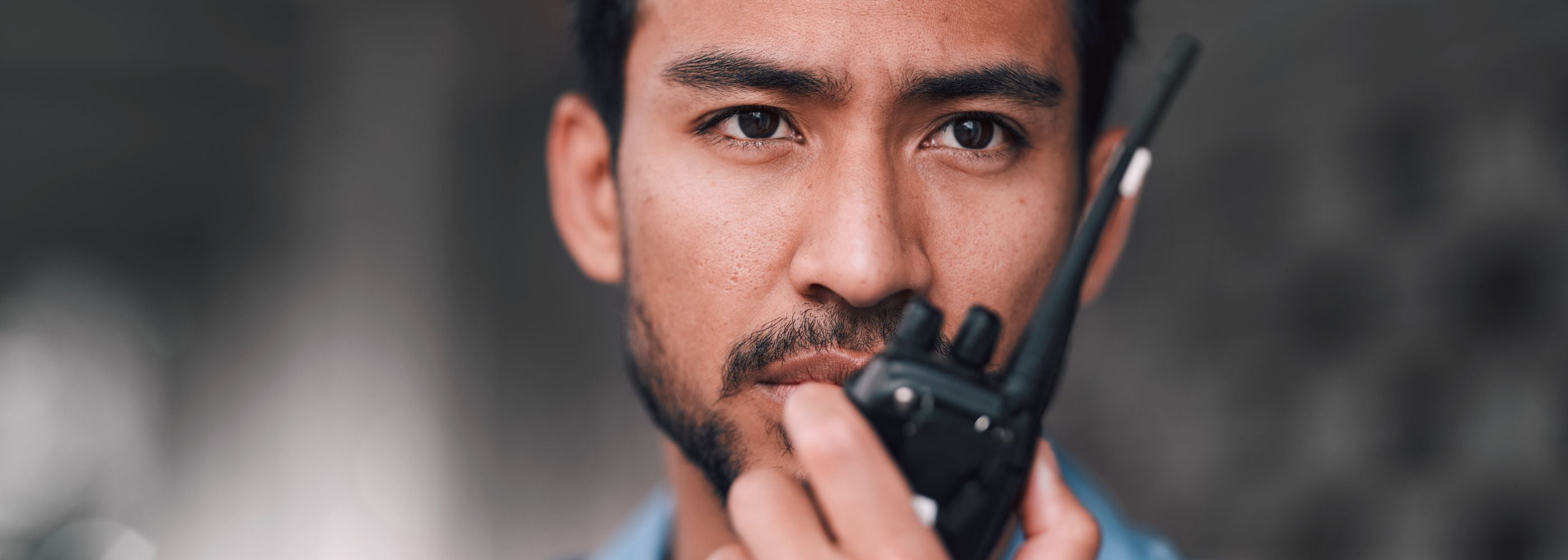 Agent_de_securite_avec_talkie_walkie_dans_la_main_en_gros_plan_sur_son_visage